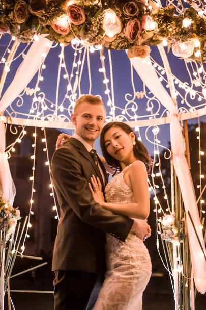 Casal feliz de pé em gazebo iluminado
  - Foto, Imagem
