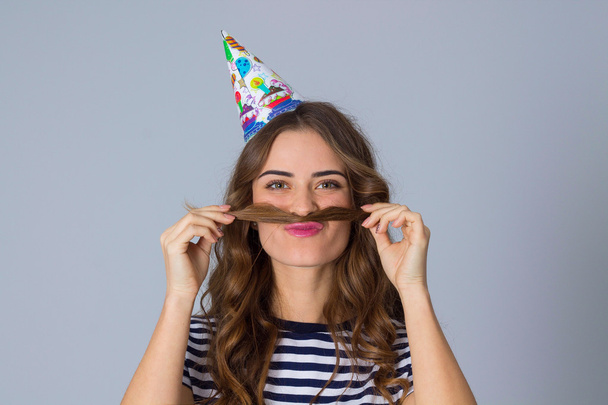 Woman in celebration cap making moustache of her hair - Photo, Image