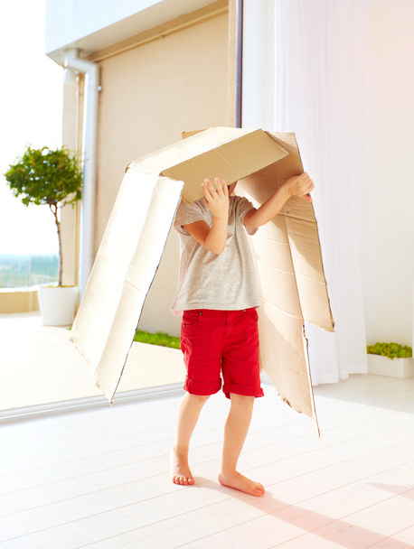 cute happy boy playing with cardboard box at home - Fotó, kép