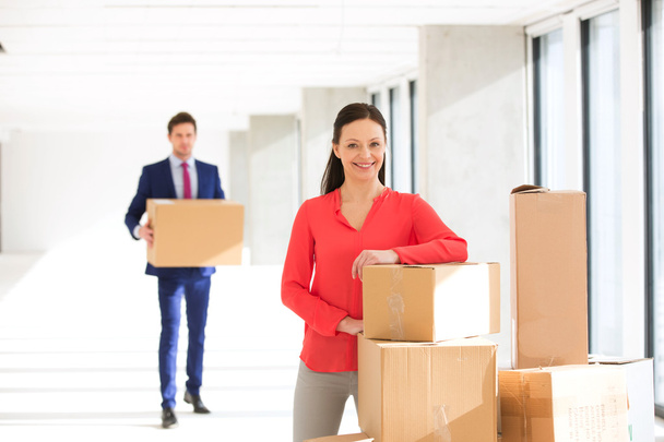 businesswoman standing by stacked boxes with colleague - Foto, Imagem