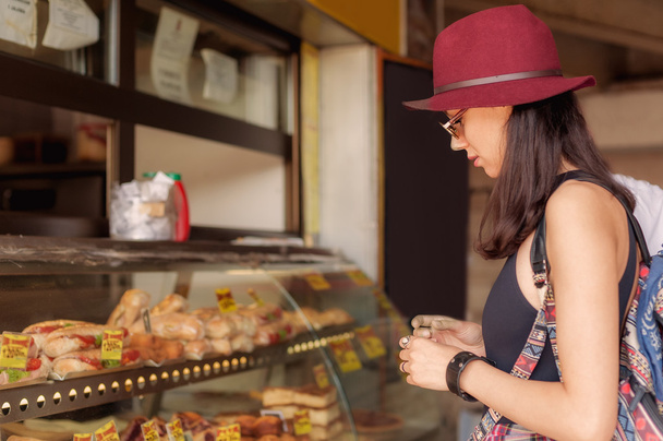 Young woman buys fresh pastries at bakery market - 写真・画像