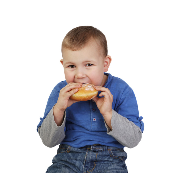 Маленький хлопчик їсть булочку
 - Фото, зображення