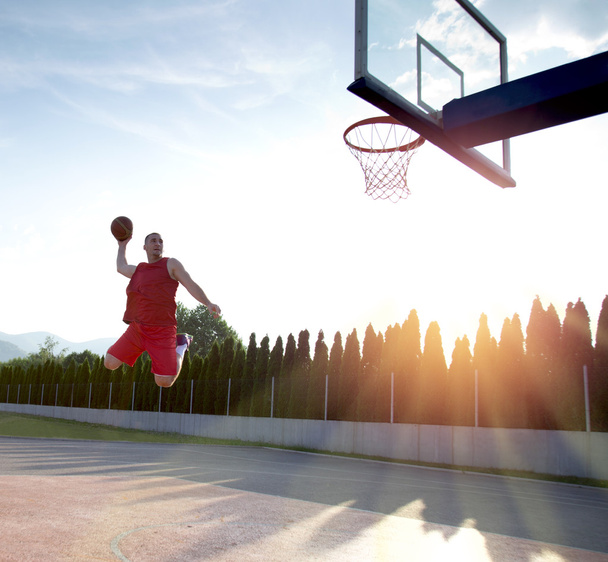 Young man jumping and making a fantastic slam dunk playing stree - Photo, Image