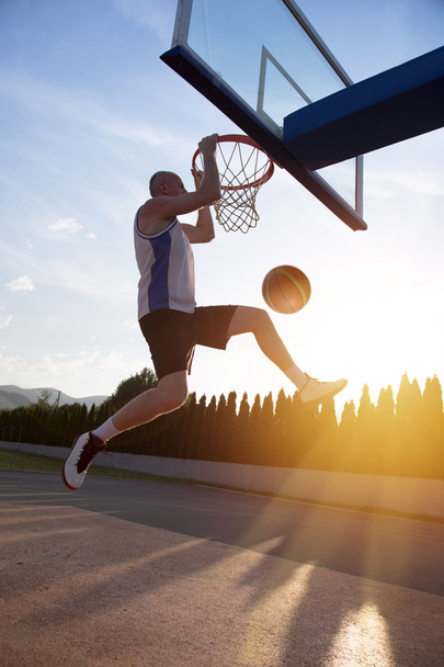 Young man jumping and making a fantastic slam dunk playing stree - Foto, immagini