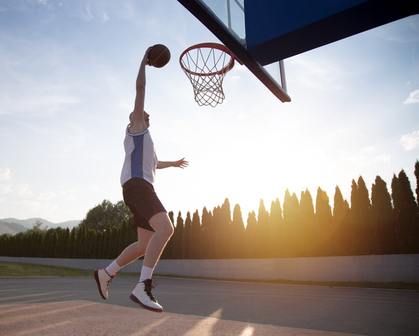 Young man jumping and making a fantastic slam dunk playing stree - Fotoğraf, Görsel