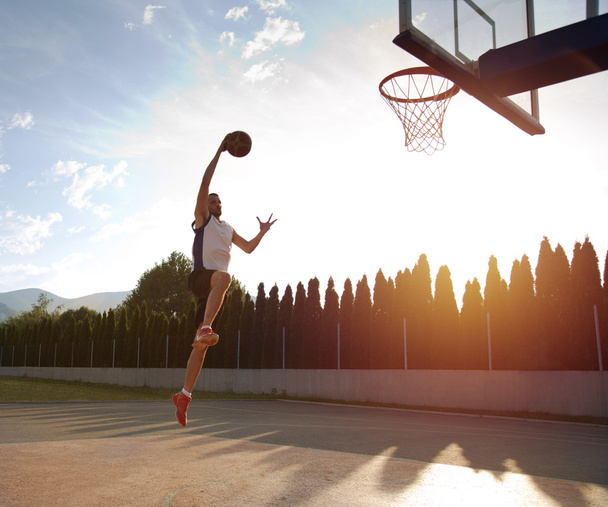 Young man jumping and making a fantastic slam dunk playing stree - Foto, immagini