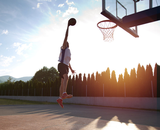 Young man jumping and making a fantastic slam dunk playing stree - Фото, изображение