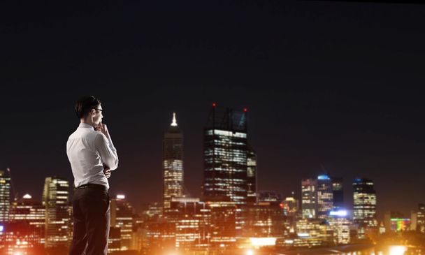 Businessman viewing night glowing city - Foto, afbeelding