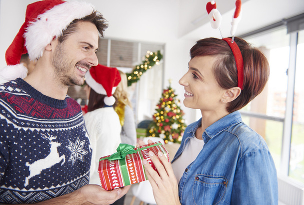 Uno de pareja dando regalos de Navidad a los demás
 - Foto, Imagen