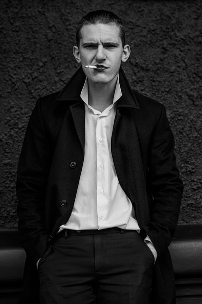 mladý muž v černém kabátě s cigaretou - Fotografie, Obrázek