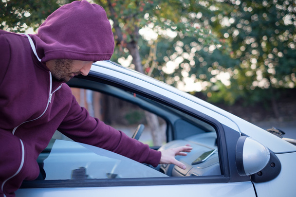 Kukuletalı hırsız arabalardan cep telefonundan çalmak - Fotoğraf, Görsel