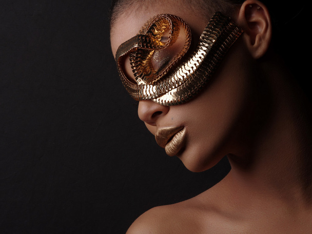 Glamour art studio portrait of an extraordinary beautiful nude african american model with perfect smooth glowing mulatto skin, make up, full golden lips, shaved haircut and gold jewelry, profile - Photo, image
