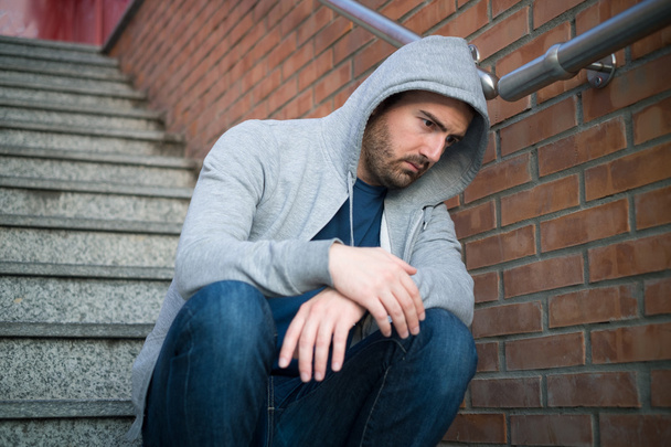 Samotny mężczyzna opierając się na miejskim ściany, siedząc na schodach - Zdjęcie, obraz