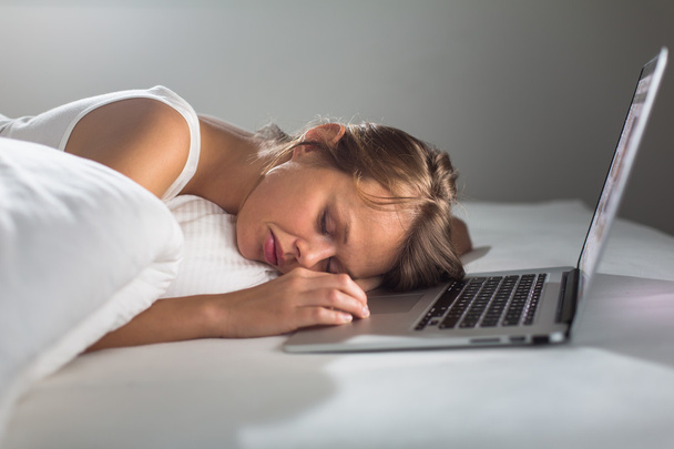 Гарненька молода жінка засинає під час роботи над своїм ноутбуком
 - Фото, зображення