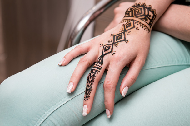 Hand painted with henna on a woman leg in salon - Photo, image