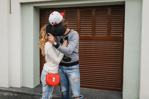 Hipster ζευγάρι στην αγάπη κρύβονται πίσω από καπέλα και φιλιά - Φωτογραφία, εικόνα