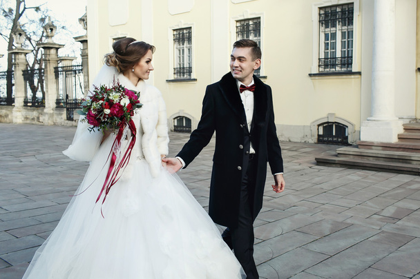 Just married walk in coats in the front of the church  - Foto, Imagem