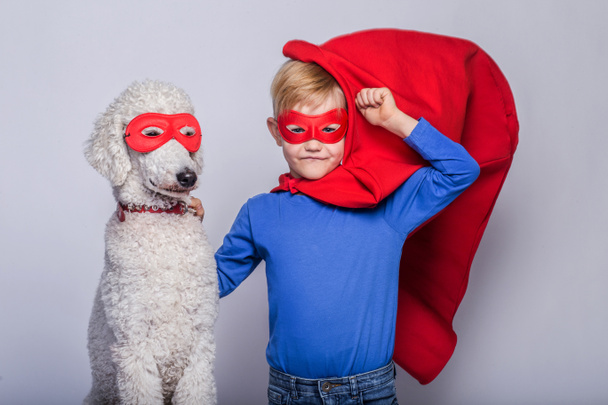 Handsome little superman with dog. Superhero. Halloween. Studio portrait over white background - Photo, Image