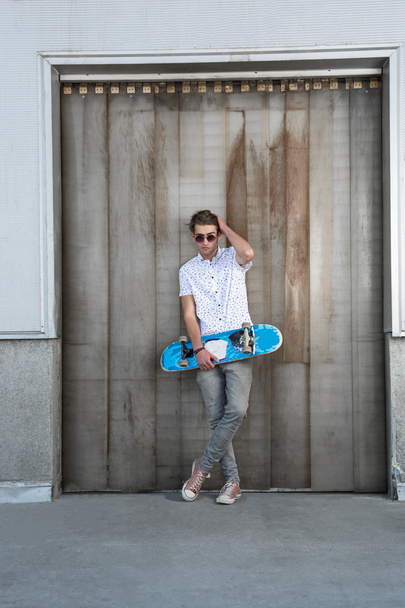 Young man in white with skateboard on city street - 写真・画像
