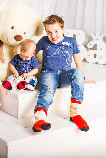 Happy boy and baby brother relaxing in white room - Photo, Image