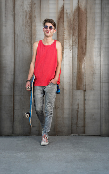 Young man with blue skateboard on city street - Fotoğraf, Görsel
