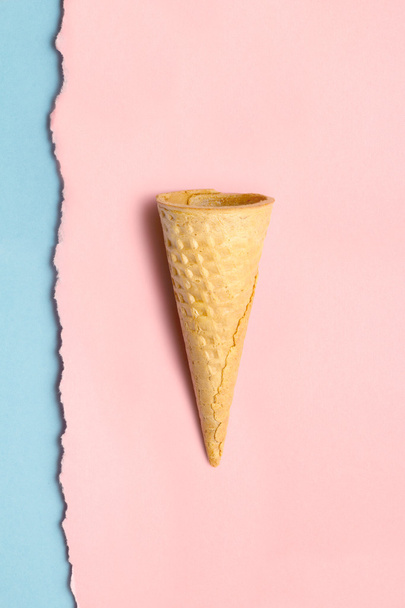 Sweet cone. Creative still life of a sweet empty wafer cone on torn wall papers background. - Фото, зображення