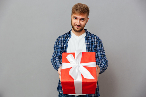 Portrait of a happy man giving gift box on camera - Foto, afbeelding