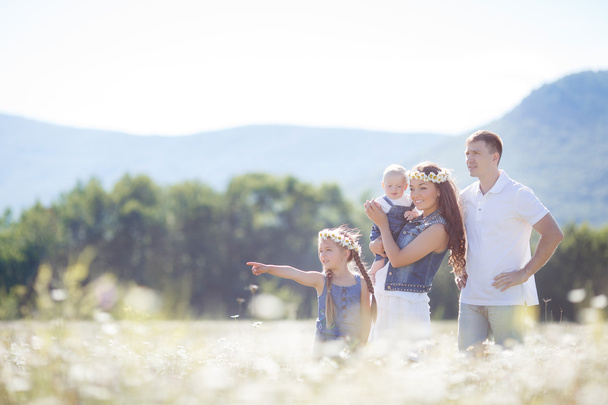 glückliche Familie auf einem Feld blühender Gänseblümchen - Foto, Bild