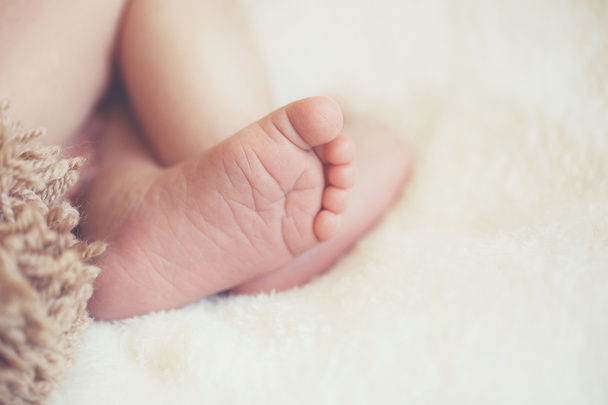 Крупный план ноги новорожденного, спящего на белом одеяле
  - Фото, изображение