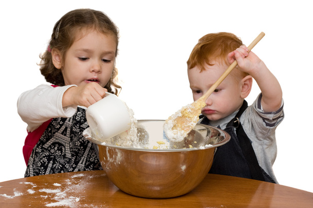 Дети измеряют и смешивают торт на кухне
 - Фото, изображение