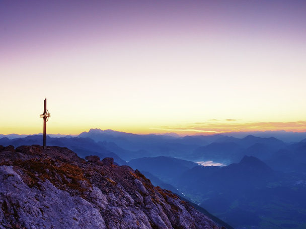 Χάλυβα σταυρό στην κορυφή του βουνού στις Άλπεις. Απότομη βραχώδη κορυφή, Χαραυγή ήλιος στον ουρανό.  - Φωτογραφία, εικόνα