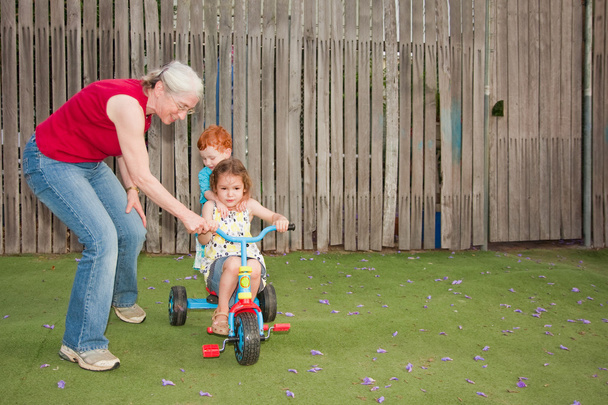 Grand-mère aider les enfants à monter trike
 - Photo, image