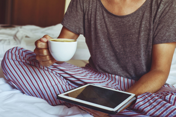 Junger Mann im Schlafanzug mit Tablet-Computer - Foto, Bild
