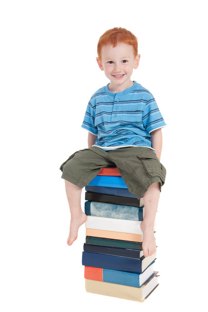 Boy sitting on stack of books - Foto, afbeelding