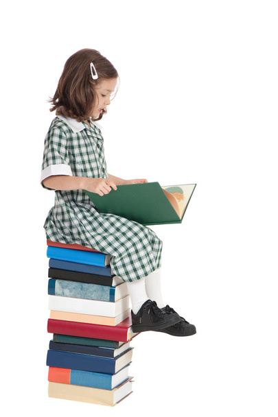 School girl sitting on book pile reading - Foto, Bild