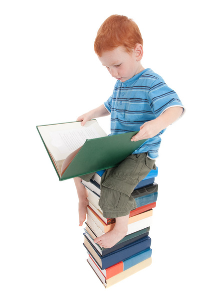 Boy reading on pile of books - Foto, afbeelding