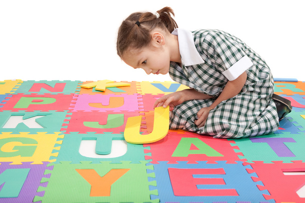 school kind in uniform afwerking alfabet brief puzzel - Foto, afbeelding