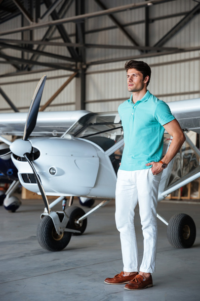 Serious attractive young man standing in front of small aircraft - Foto, immagini