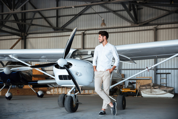 Smiling young man standing near small aircraft - Foto, immagini