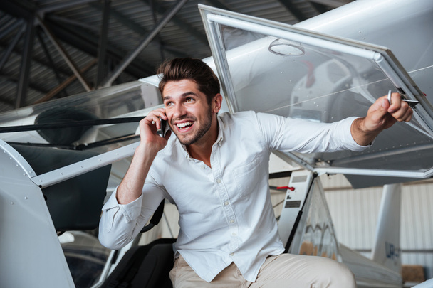 Smiling man talking on cell phone in small aircraft - Φωτογραφία, εικόνα