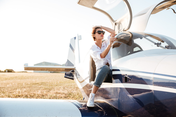 Woman in sunglasses sitting in small private plane - Фото, изображение