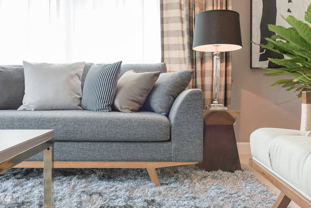 Reihe Kissen auf grauem Sofa mit schwarzer Lampe im Wohnzimmer  - Foto, Bild
