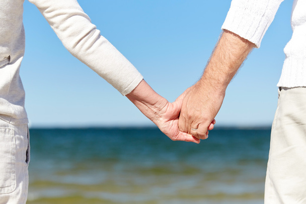 Nahaufnahme eines älteren Ehepaares beim Händchenhalten am Strand - Foto, Bild