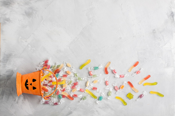 Balde de Halloween com doces e jujuba em backgr concreto cinza
 - Foto, Imagem