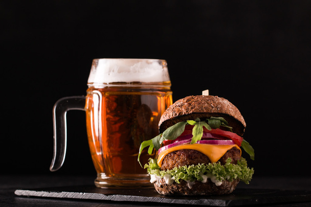 Fresh and tasty hamburger with a beer on a wooden table. - Фото, зображення