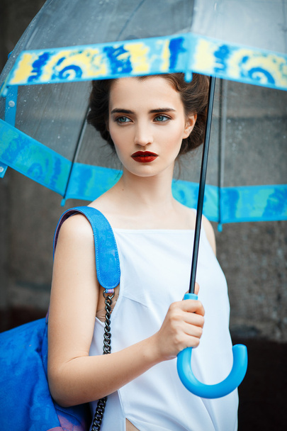 Fashionable young woman with retro hair, umbrella posing at street - Fotoğraf, Görsel
