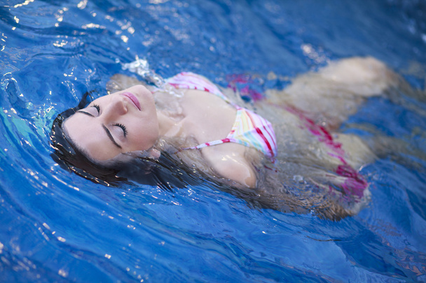 Jovem mulher atraente flutuando em uma piscina
 - Foto, Imagem
