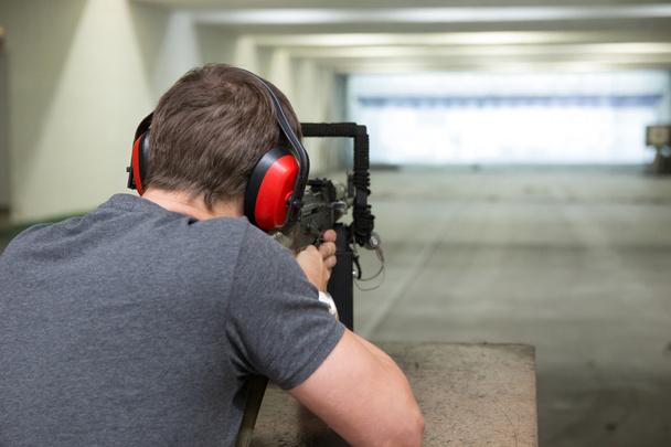 El hombre está apuntando un arma en el campo de tiro
 - Foto, Imagen