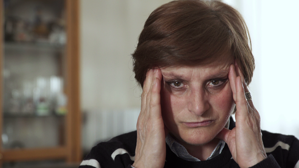 reife Frau mit Kopfschmerzen reibt sich die Schläfen  - Filmmaterial, Video