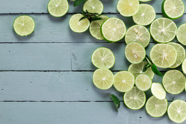 Lime background. Fresh limes with slices and mint leaves around. - Foto, immagini